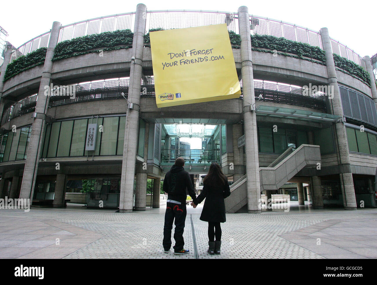 Un jeune couple regarde un Post-IT géant de 5 m x 5 m près de la gare de  Liverpool Street à Londres pour célébrer le 30ème anniversaire de la marque  Post-it et