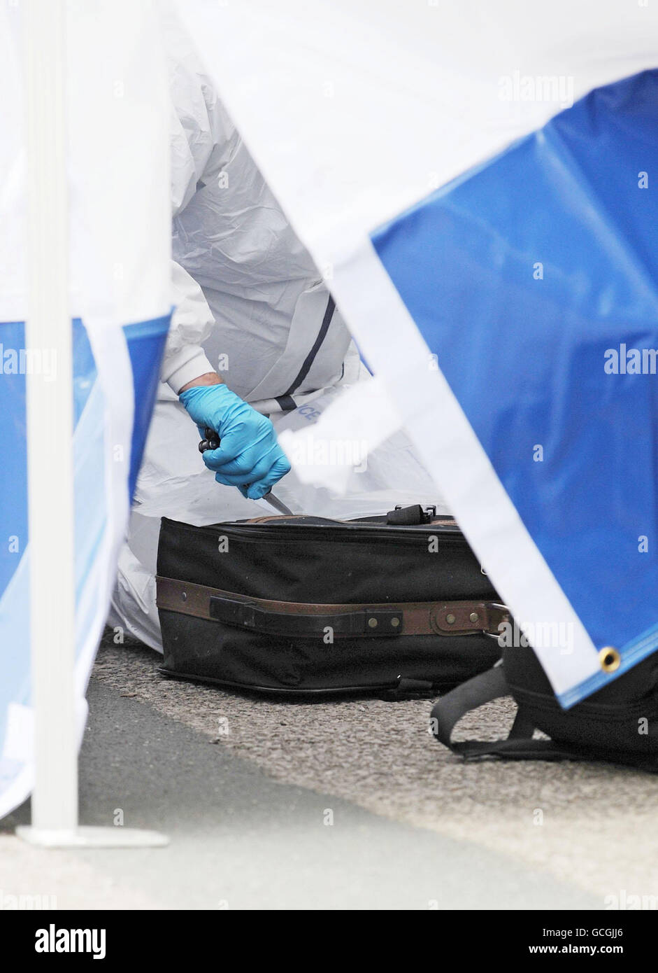 Un policier se prépare à placer une valise dans un sac de preuves de police près de la scène de Shipley où des restes ont été trouvés dans la rivière aire. Banque D'Images
