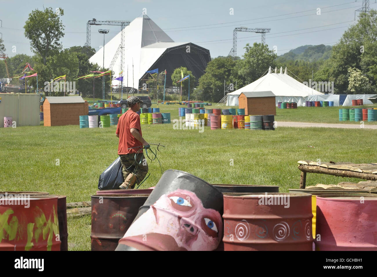 Un ouvrier du festival tidies des champs où le marché sera, avec l'emblématique étape Pyramide dans le fond comme les préparatifs pour le festival de musique Somerset se passent bien avec le temps sec et le ciel ensoleillé sur le site de 1000 acres à la ferme de digne, Pilton, Somerset. Banque D'Images