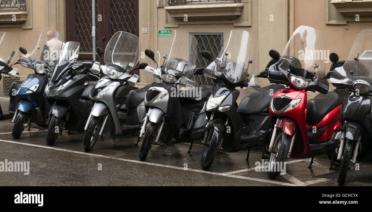 Les motos garées dans une rangée à l'extérieur d'un bâtiment ; Florence, Italie Banque D'Images