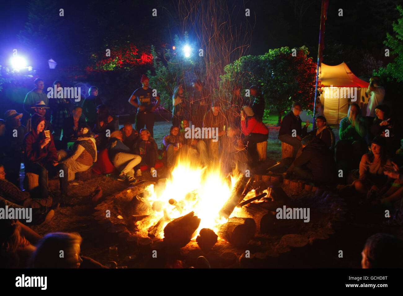 Les fêtards se tiennent au chaud par un feu de camp au Body and Soul Festival pour marquer la veille de la Soltace d'été au château de Ballinlough dans le comté de Meath. Banque D'Images