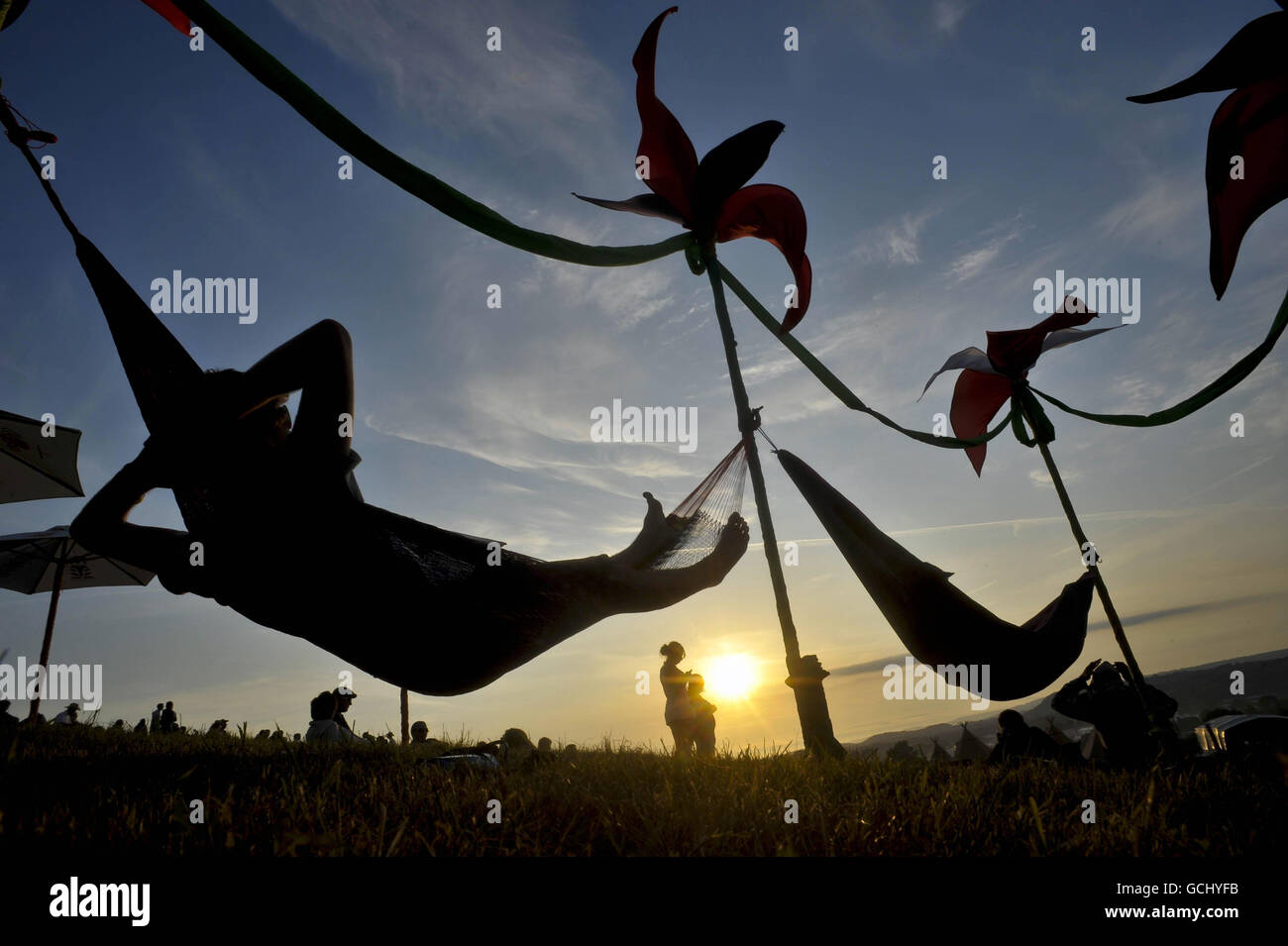 Les fêtards se déchargent de leurs pieds et se rafraîchissez dans des hamacs pendant le coucher du soleil au Glastonbury Festival 2010, digne Farm, Pilton, Somerset. Banque D'Images