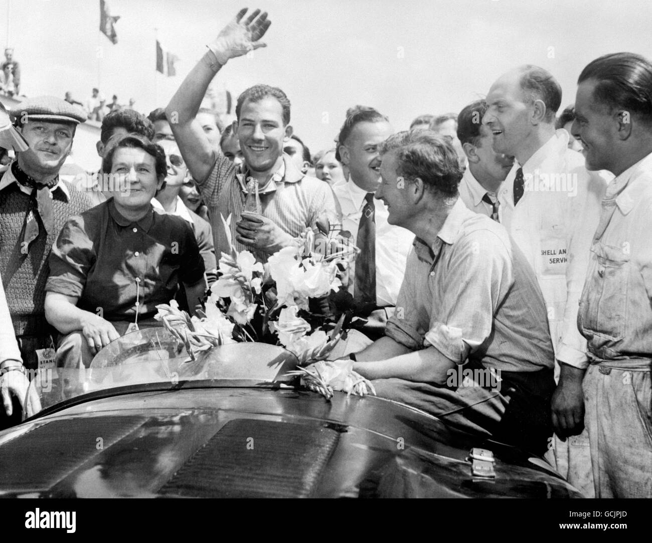 Les deux pilotes britanniques triomphants, Stirling Moss (Waving) et Peter Whitehead, assis à droite, avec la Jaguar après leur victoire.Ils ont remporté la course de voitures de sport de 12 heures à Reims, en France, en couvrant 1,274 miles à une vitesse moyenne de 105.5 miles par heure. Banque D'Images