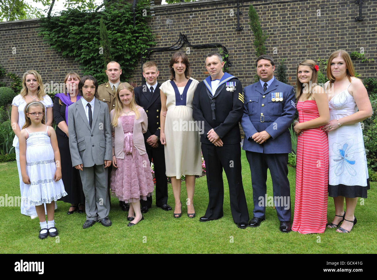 Samantha Cameron (à gauche), épouse du Premier ministre britannique David Cameron, pose pour une photographie avec le personnel de service et les membres de la famille, lors d'une réception à Downing Street, dans le centre de Londres, en aide aux billets de troupes. Banque D'Images