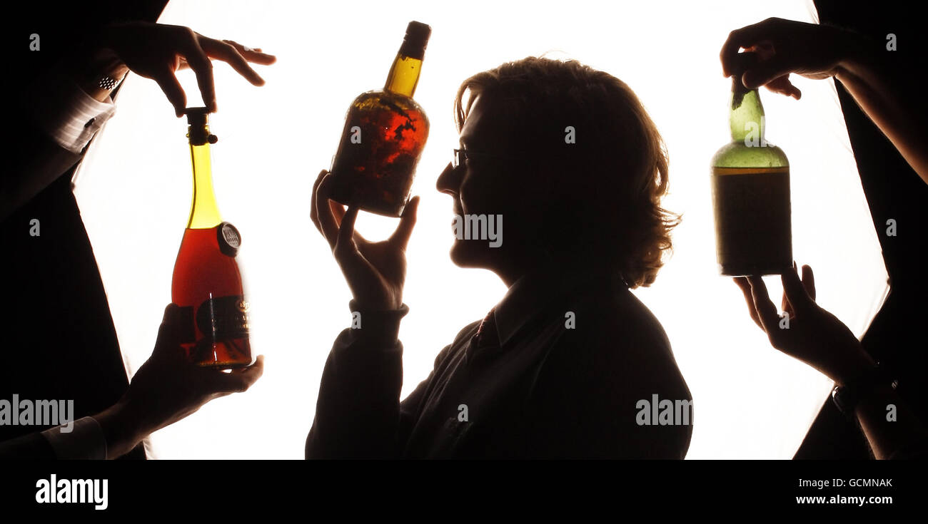 Andy Bell, spécialiste du whisky McTear's Auctioneers, regarde trois bouteilles rares de whisky et de cognac du XIXe siècle qui devraient aller chercher plusieurs milliers de livres chacune aux enchères, au cours d'une séance photo aux enchères McTear's Auctioneers, à Glasgow, en Écosse. Banque D'Images