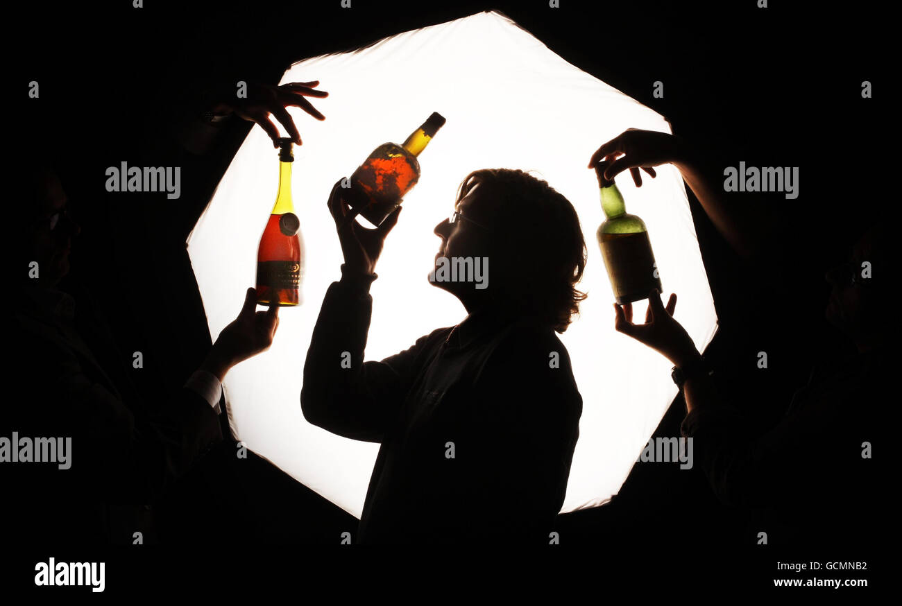 Andy Bell, spécialiste du whisky McTear's Auctioneers, regarde trois bouteilles rares de whisky et de cognac du XIXe siècle qui devraient aller chercher plusieurs milliers de livres chacune aux enchères, au cours d'une séance photo aux enchères McTear's Auctioneers, à Glasgow, en Écosse. Banque D'Images