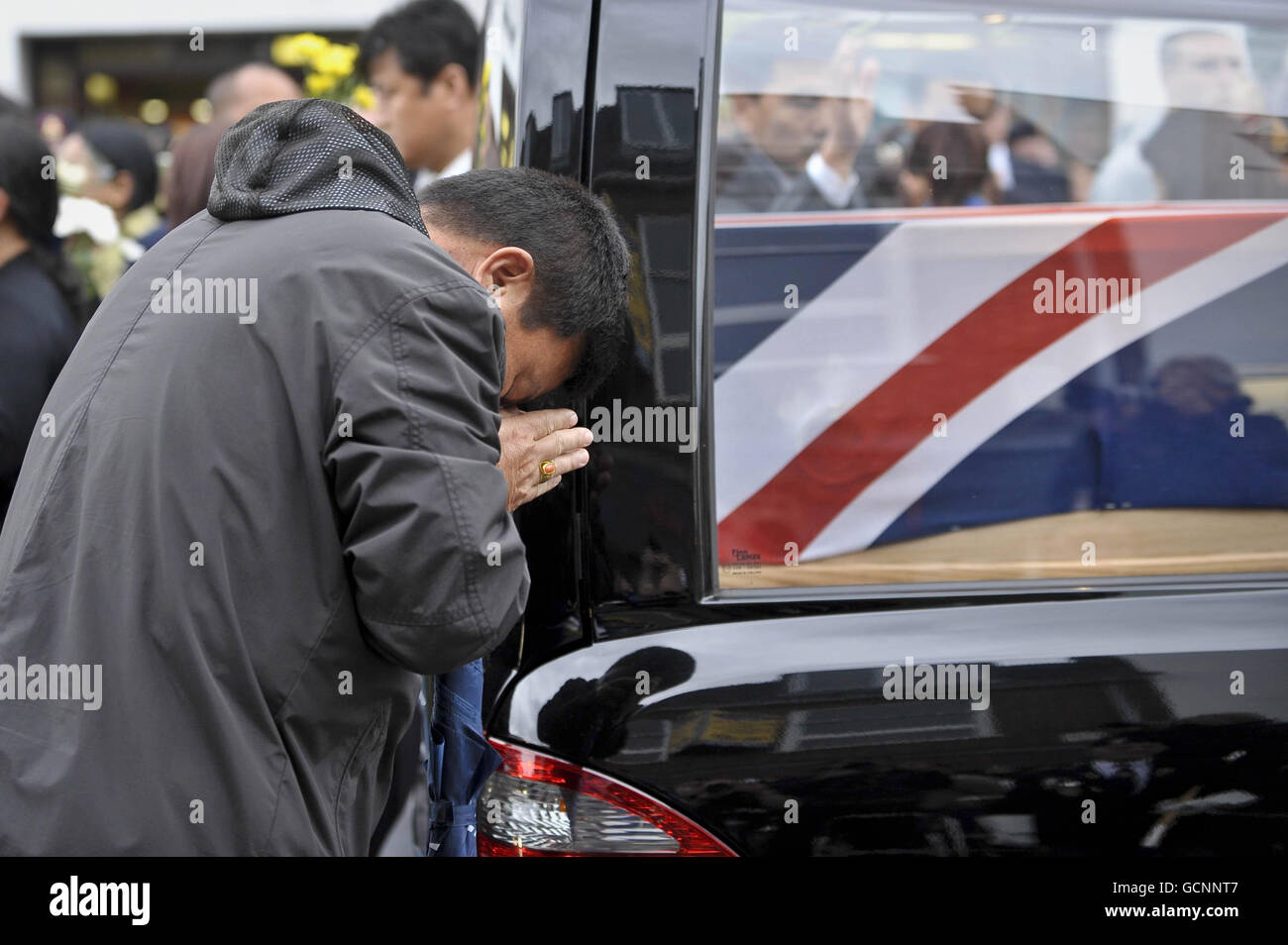 Un homme fait une action de prière à côté d'un drapeau d'Union drapé cercueil pendant le rapatriement de Sapper Darren Foster, 20, du 21 Engineer Regiment et Sapper Ishwor Gurung, 21, du 36 Engineer Regiment à Wootton Bassett, Royaume-Uni. Banque D'Images