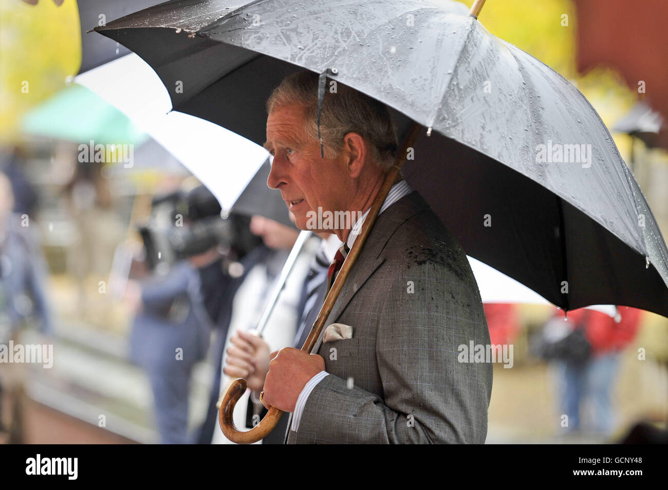 Le Prince de Galles avec son parapluie après une grosse déverse dans les Jardins botaniques nationaux du pays de Galles à Carmarthen alors qu'il poursuit sa tournée en Grande-Bretagne pour promouvoir son initiative de vie durable. Banque D'Images