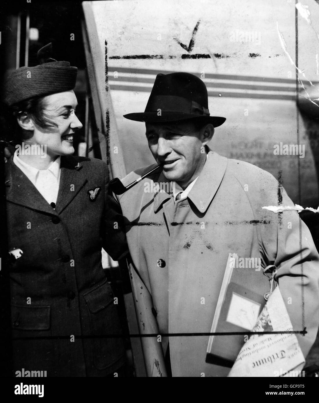 Bing Crosby, toujours en train de fumer sa pipe préférée, s'entretient avec l'hôtesse de Bra Thelma Gillan (de Knightsbridge) avant de quitter l'aéroport de Northolt pour Paris.Crosby, qui a fait un court séjour en Angleterre pour jouer un match de golf en partenariat avec Bob Hope, est de faire un film en France le 22 septembre 1952 Banque D'Images