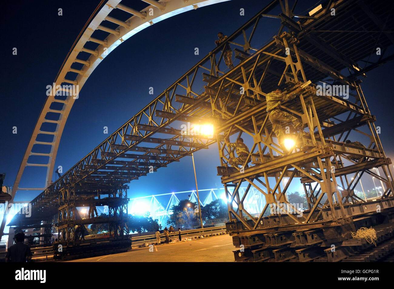 L'armée poursuit les travaux de construction tout au long de la nuit sur un pont de remplacement à l'extérieur du stade Nehru, le stade principal des Jeux du Commonwealth de 2010 à New Delhi, en Inde. Banque D'Images