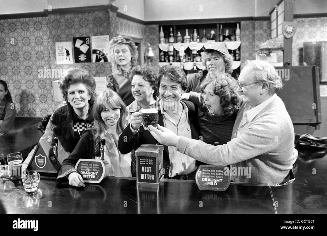 L'acteur de cinéma américain Dustin Hoffman, au centre, essaie une pinte de bière dans le 'Rovers Return'. Il visitait le studio de télévision de Manchester où la longue série britannique 'Coronation Street' est faite. Pat Phoenix, est à l'extrême gauche, tandis que Fred Feast sert la pinte comme d'autres membres de la distribution regardent. Banque D'Images