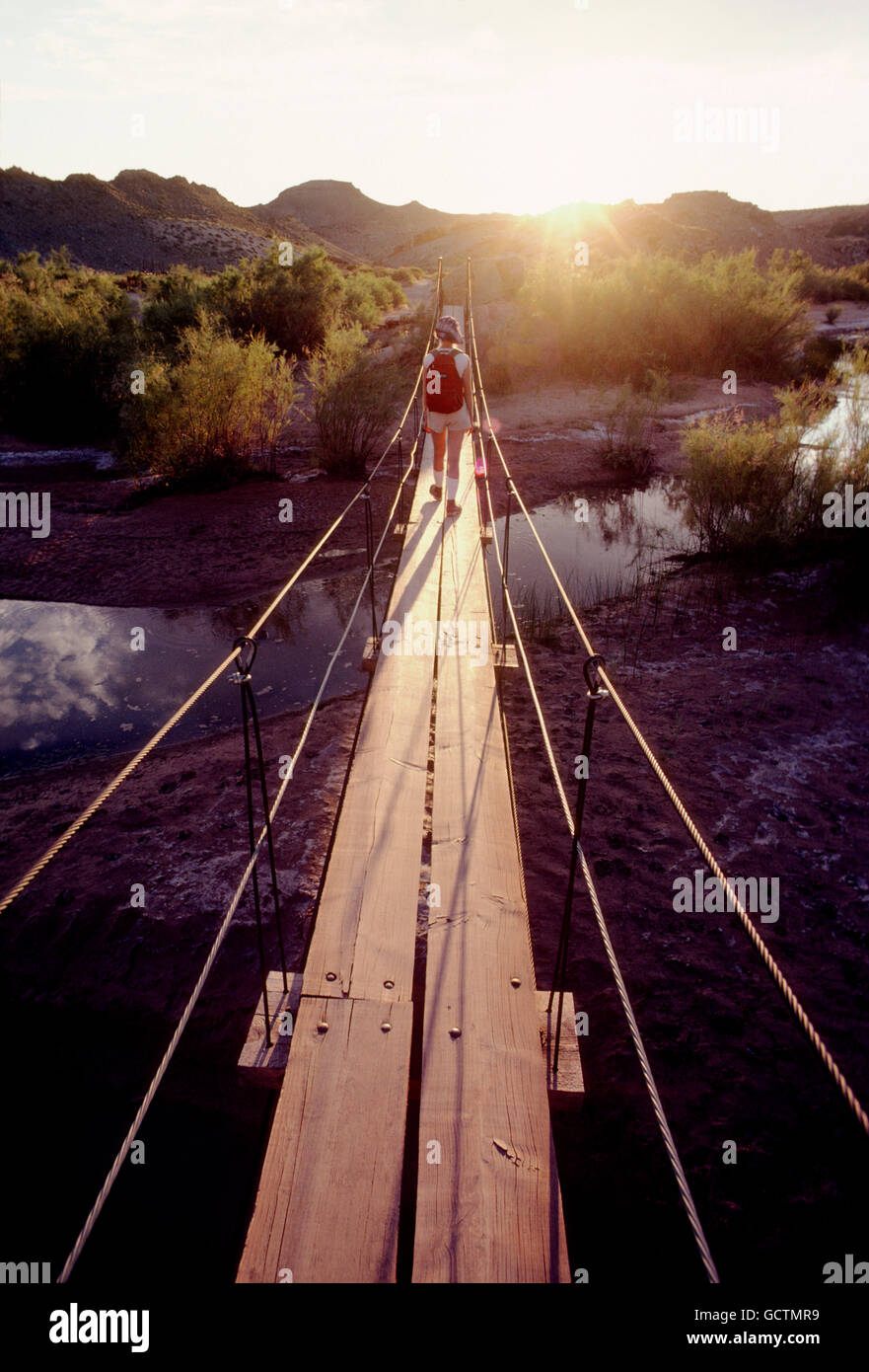 Female hiker crossing passerelle au coucher du soleil ; le sud de l'Utah désert ; USA Banque D'Images