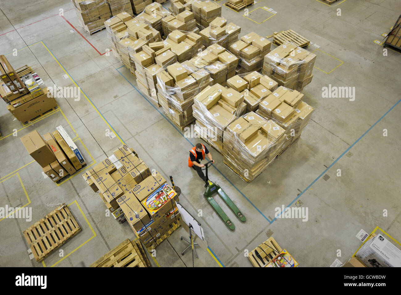 Un employé d'Amazon pousse un palettiseur parmi les boîtes du centre de distribution d'Amazon, Swansea, pays de Galles. Banque D'Images