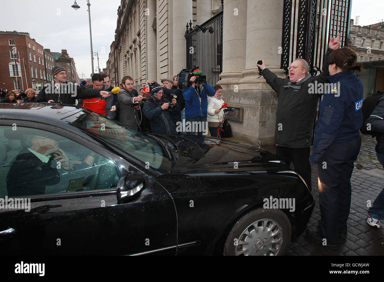 Un manifestant bloque l'entrée alors que la ministre du Tourisme, de la Culture et du Sport Mary Hanafin s'approche des bâtiments gouvernementaux à Dublin, alors que le cabinet rencontre le ministre irlandais des Finances Brian Lenihan pour demander au gouvernement de demander un prêt de sauvetage au Fonds monétaire international (FMI) et à l'Europe. Banque D'Images