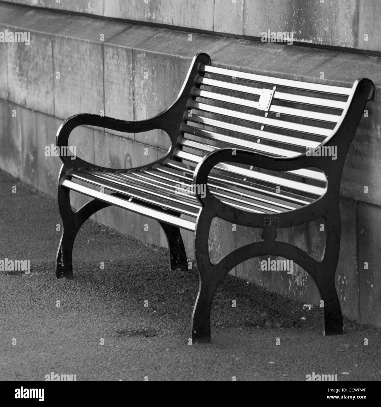 Black metal banc le long d'un mur de béton ; Édimbourg, Écosse Banque D'Images