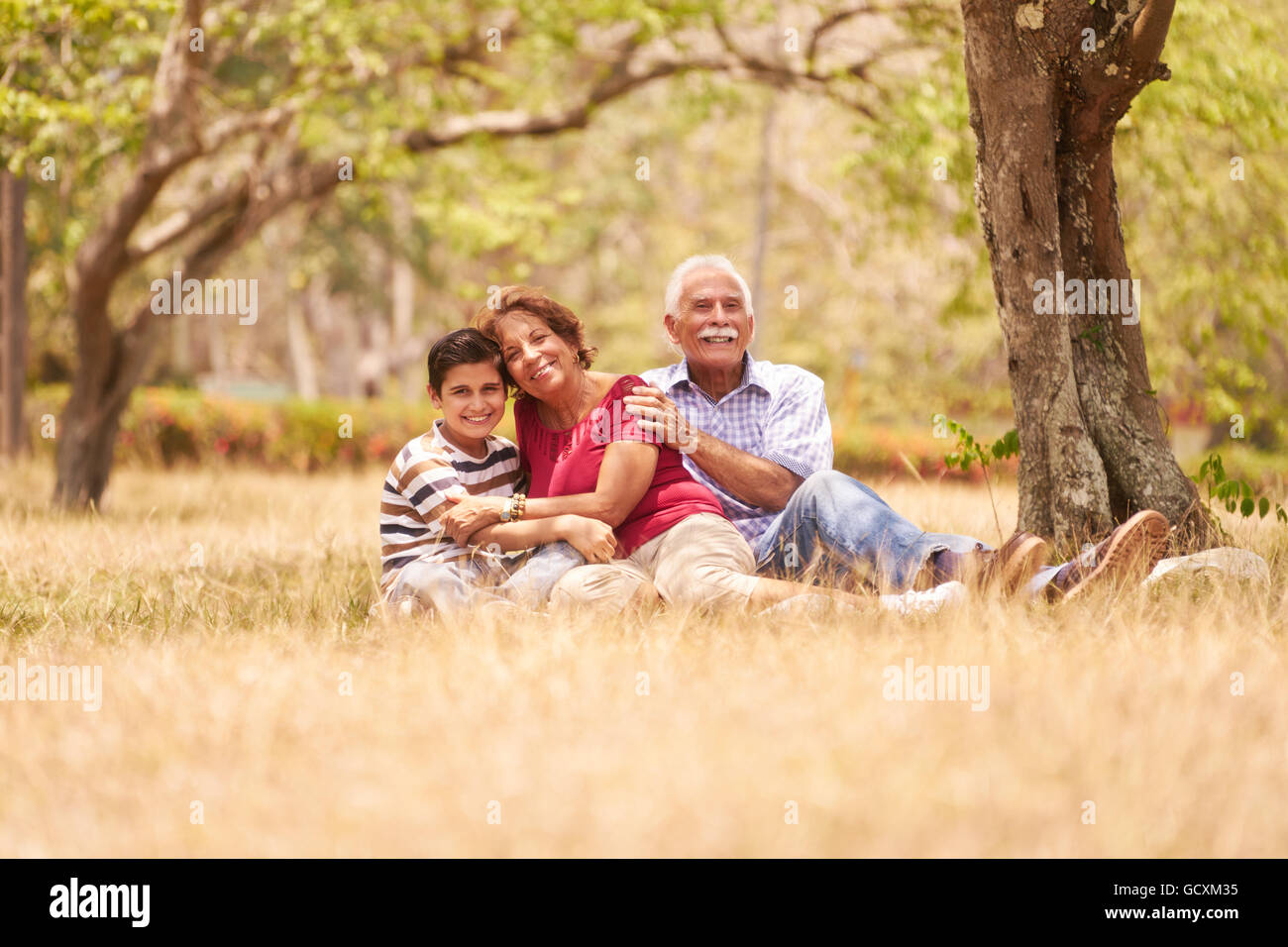 Les personnes âgées, en couple, une femme et un homme âgés. Une famille s'amusant avec papi et mamie hugging boy at picnic Banque D'Images