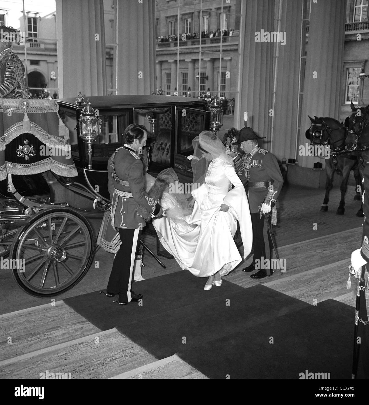 La princesse Anne hante sa robe et garde un œil sur son train pendant qu'elle quitte le Glass Coach à son retour au Palais de Buckingham avec le capitaine Mark Phillips après leur mariage à l'abbaye de Westminster. Banque D'Images