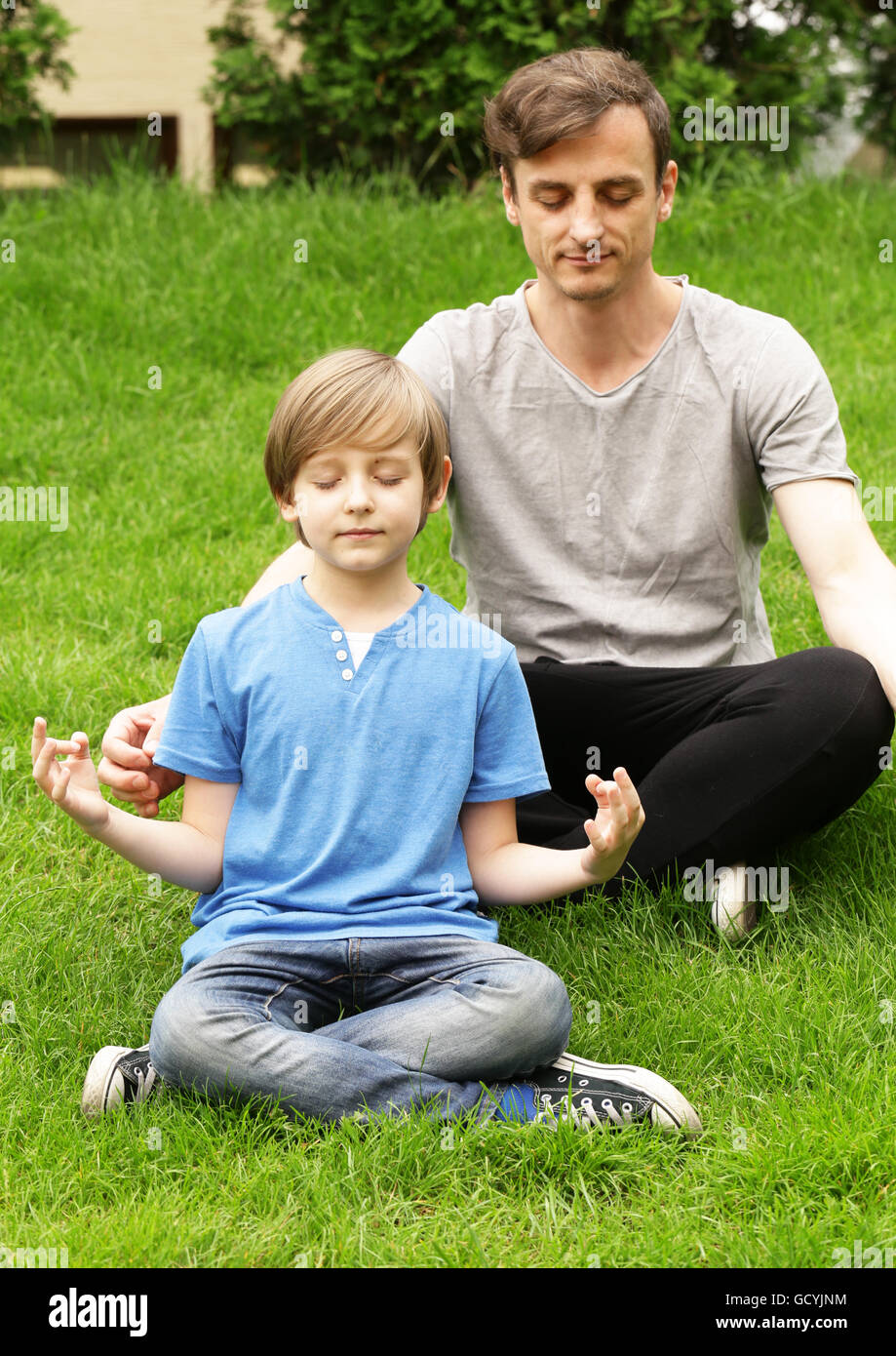Père et fils assis sur l'herbe verte et méditer Banque D'Images