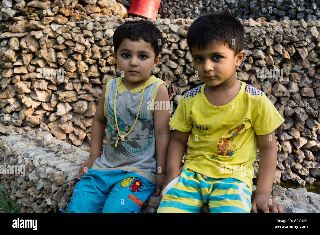 Deux enfants assis dans un joli parc avec des robes colorées Banque D'Images