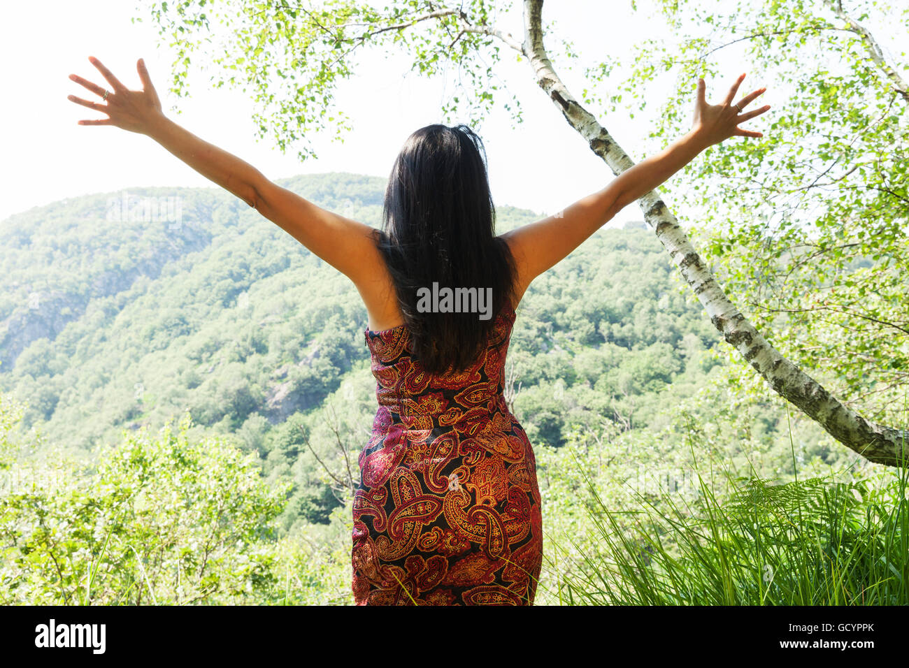 Femme élégante à bras ouverts dans la forêt Banque D'Images