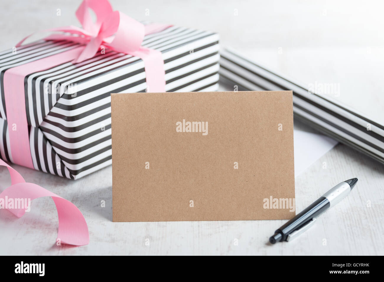 Message d'accueil vide carte kraft avec stylo. Cadeau Enveloppé de papier d'emballage et de rouler en arrière-plan. Banque D'Images