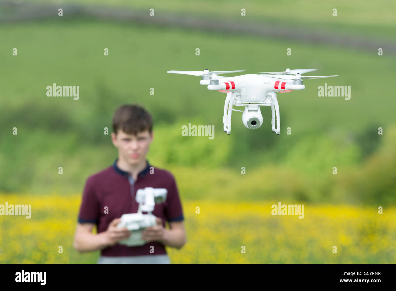 Teenage boy l'exploitation d'un drone quadcopter en campagne, UK. Banque D'Images