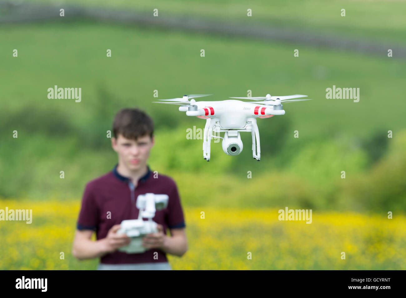 Teenage boy l'exploitation d'un drone quadcopter en campagne, UK. Banque D'Images