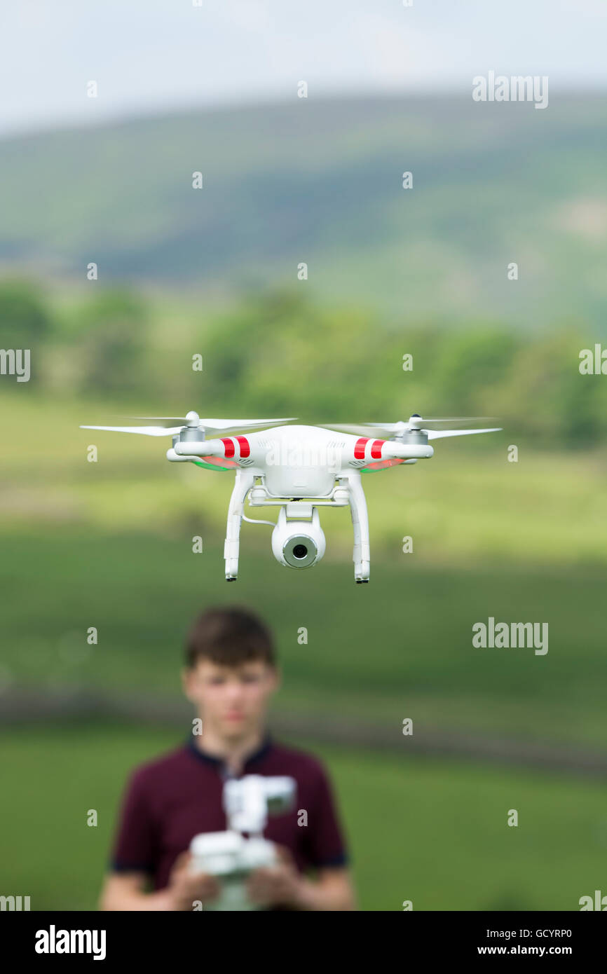 Teenage boy l'exploitation d'un drone quadcopter en campagne, UK. Banque D'Images