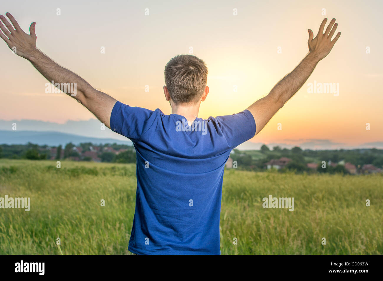 Jeune homme heureux dans un champ de blé au coucher du soleil Banque D'Images