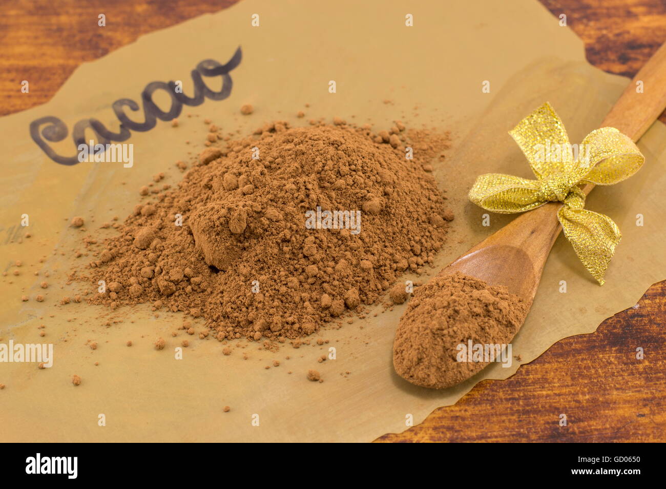 Cacao poudre, cuillère en bois et des bonbons sur papier cuisson foncé Banque D'Images