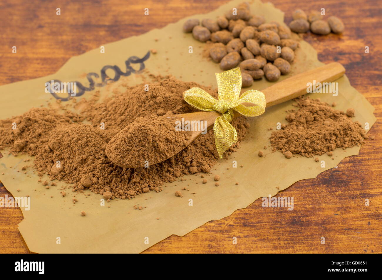 Cacao poudre, cuillère en bois et des bonbons sur papier cuisson foncé Banque D'Images