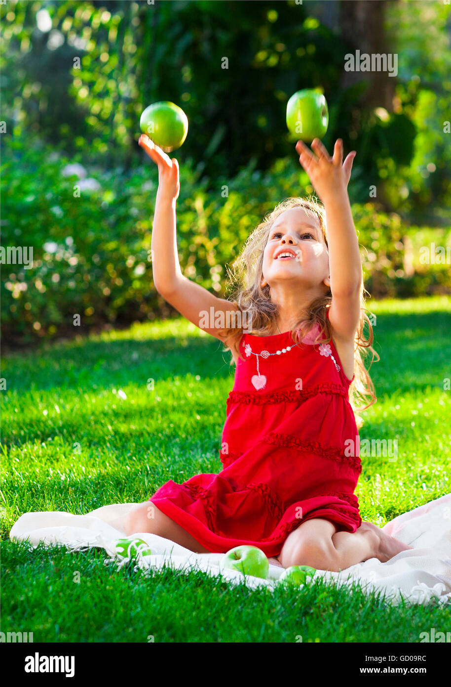 Funny little girl avec la pomme verte dans le parc d'été Banque D'Images