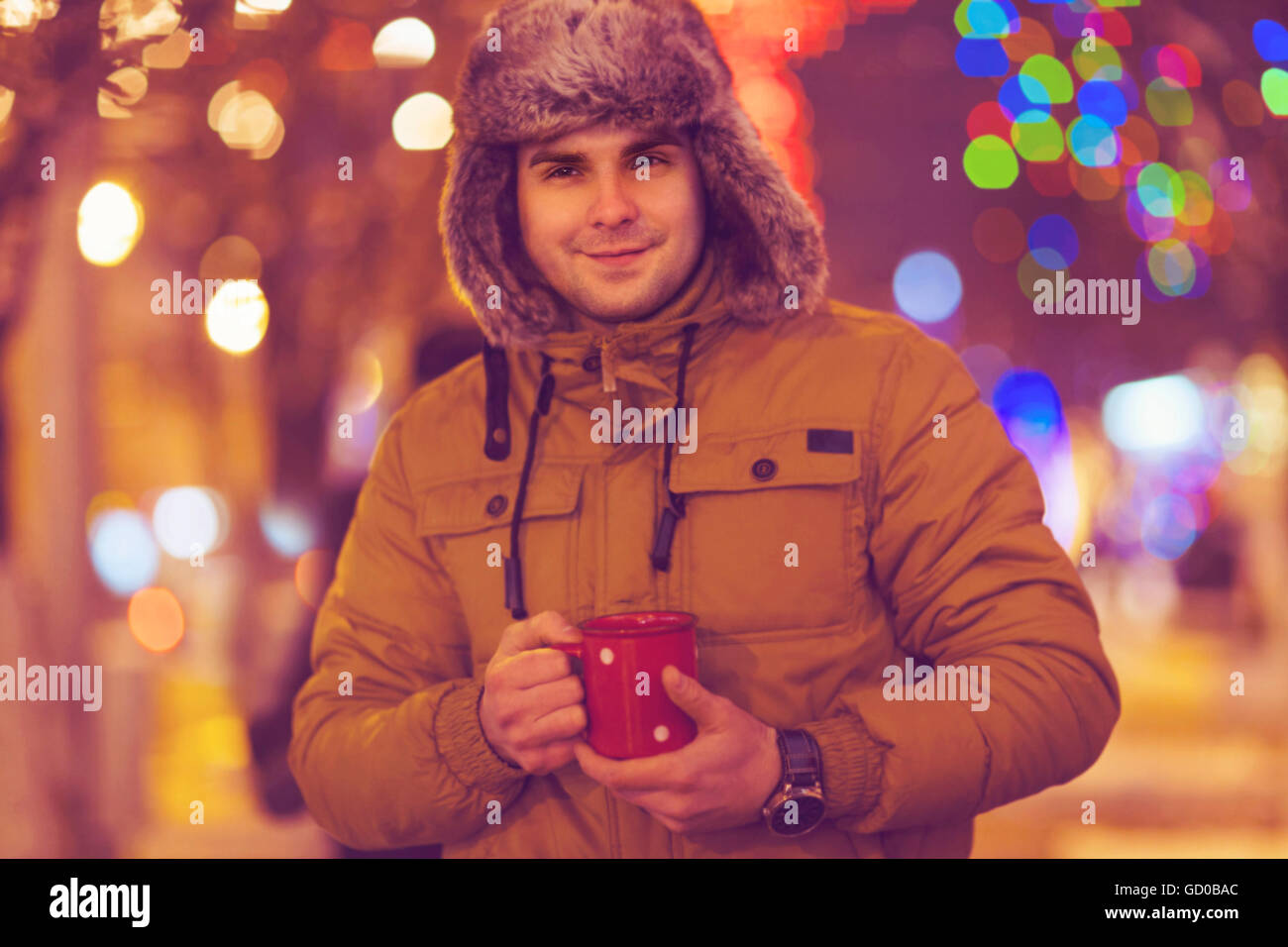Portrait de jeune homme à boire le thé en hiver en plein air sur les lumières de Noël Banque D'Images