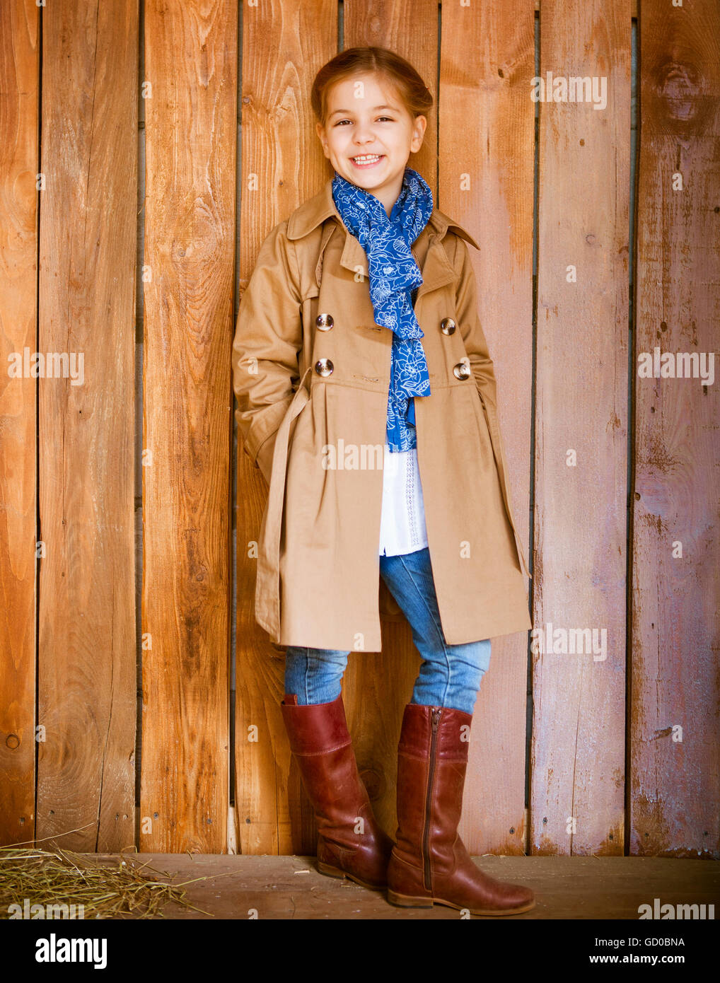 Cute little girl wearing vêtements automne debout sur fond de bois Banque D'Images