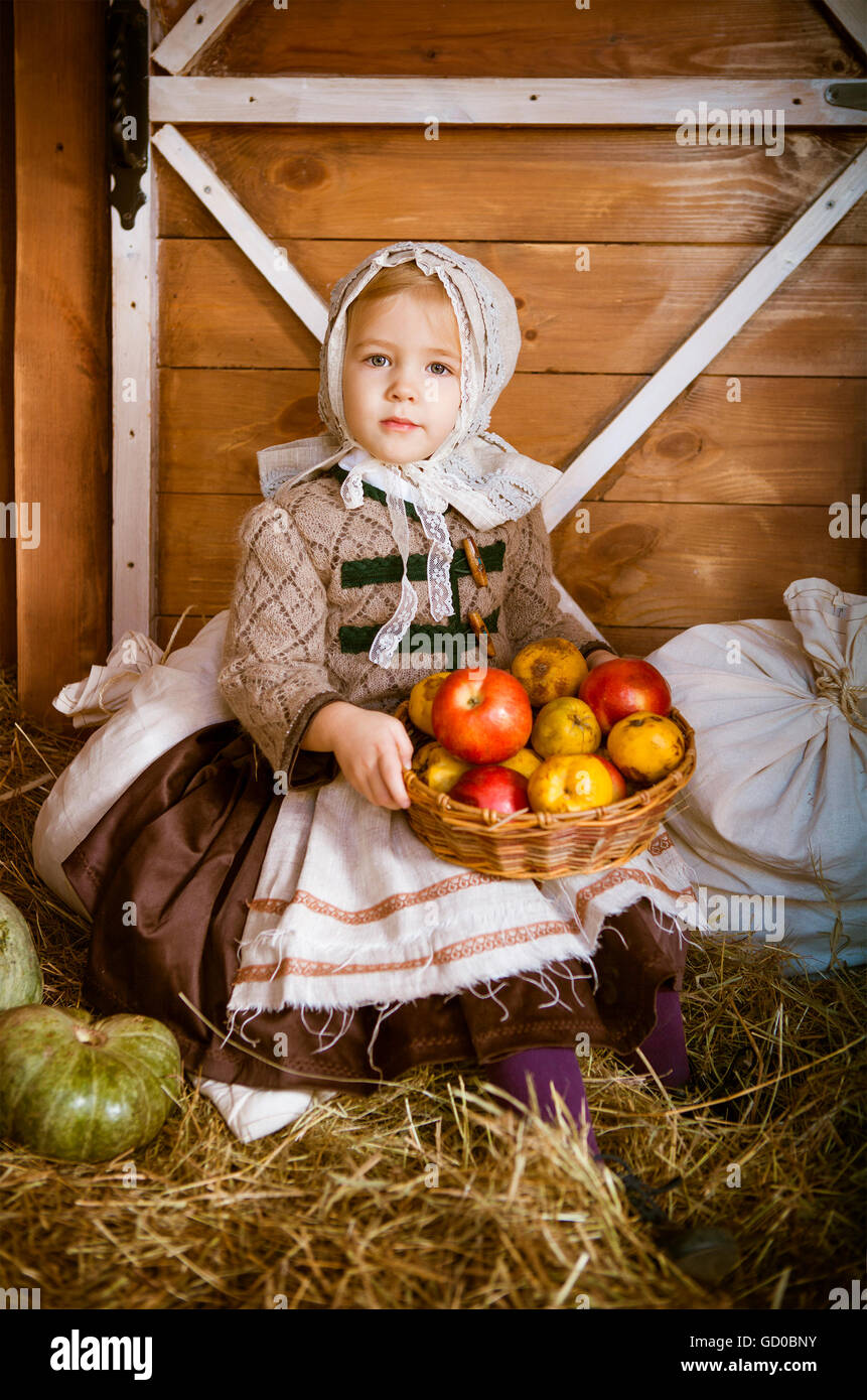 Style vintage photo de little smiling girl holding basket à la ferme avec des pommes Banque D'Images