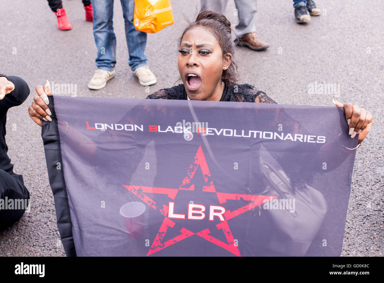 Brixton, Londres, Royaume-Uni. 9 juillet 2016. Les contestataires révolutionnaires Black assis dans la rue. Des centaines de vies noir Question partisans ont marché sur le poste de police local avant qu'un sit-in de protestation sur Brixton High Street qui a rues de Londres à l'arrêt. La marche est en réponse à la fusillade mortelle de Philando Castille au Minnesota et Alton Sterling en Louisiane. Credit : Nicola Ferrari/Alamy Live News. Banque D'Images