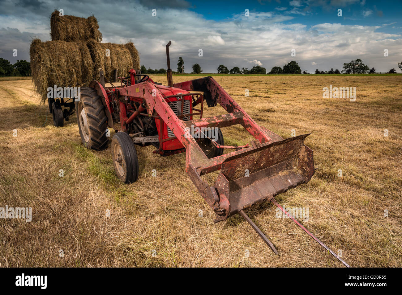 Wiltshire, Royaume-Uni. 10 juillet, 2016. Royaume-uni - un vintage tracteur est utilisé pour recueillir dans la récolte de foin, comme les nuages de tempête approche, dans le Wiltshire, Angleterre. Credit : Terry Mathews/Alamy Live News Banque D'Images