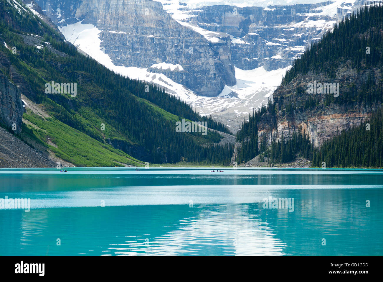 Les gens de l'aviron sur canoës à Lake Louise en Alberta, Canada. Les eaux d'été sont toujours et les montagnes en arrière-plan en font un site populaire. Banque D'Images