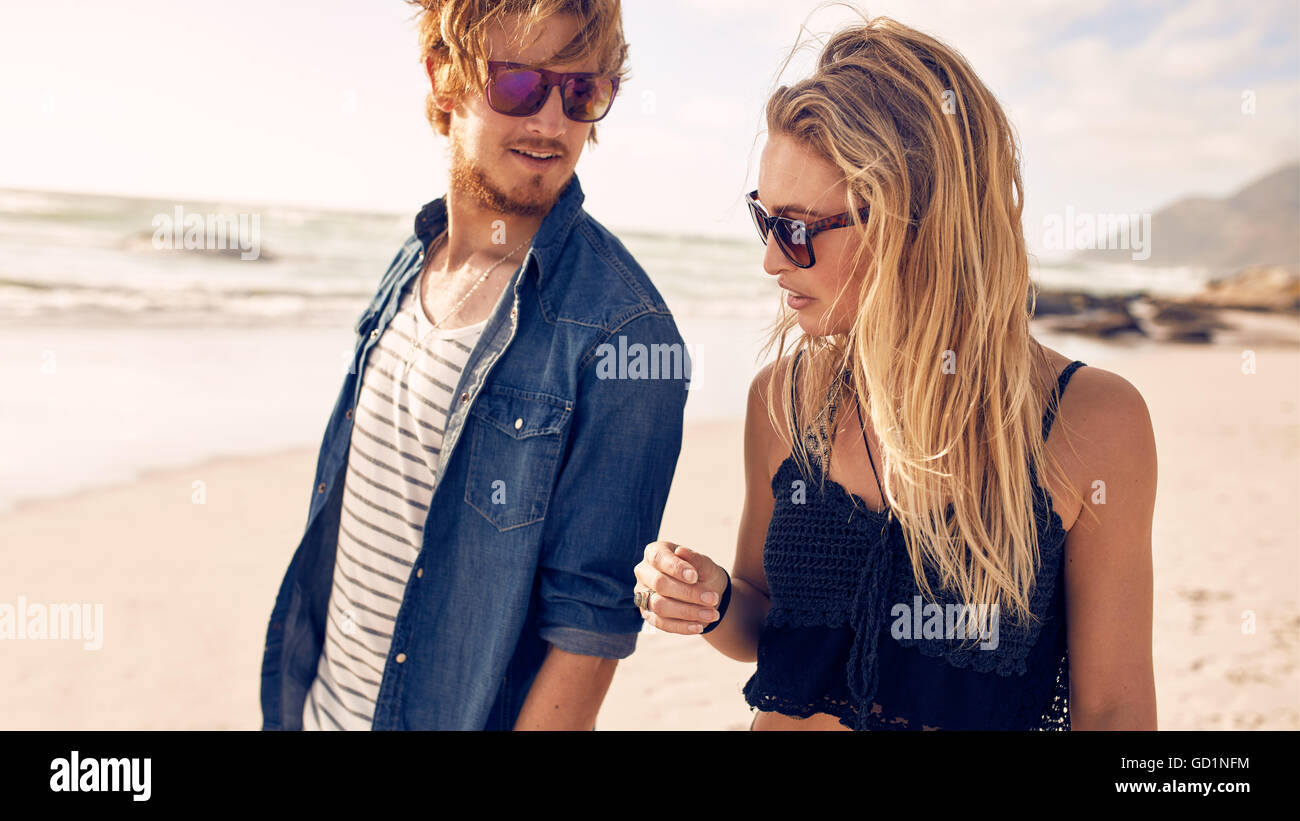 Closeup portrait of young couple parler tout en marchant le long d'une plage. Jeune homme et femme se promenant sur une plage. Banque D'Images