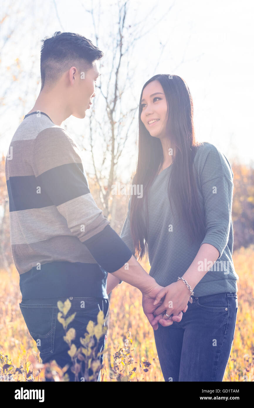 Un jeune couple asiatique appréciant Un moment romantique ensemble en plein air dans Un parc en automne et tenant les mains dans la chaleur de la lumière du soleil pendant le comte... Banque D'Images