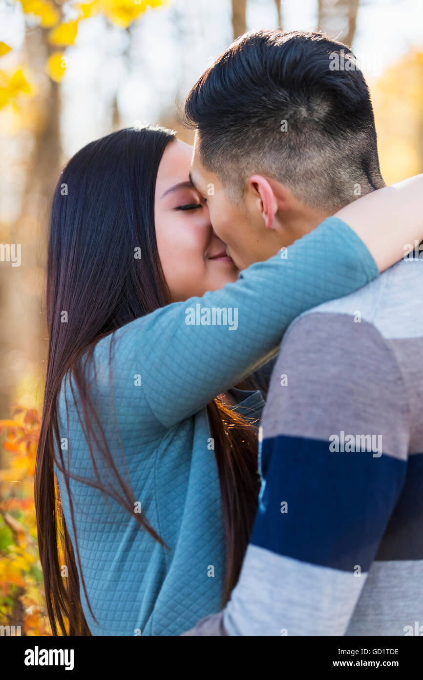 Un jeune couple asiatique appréciant Un moment romantique ensemble en plein air dans Un parc en automne et s'embrassant dans la chaleur de la lumière du soleil pendant... Banque D'Images