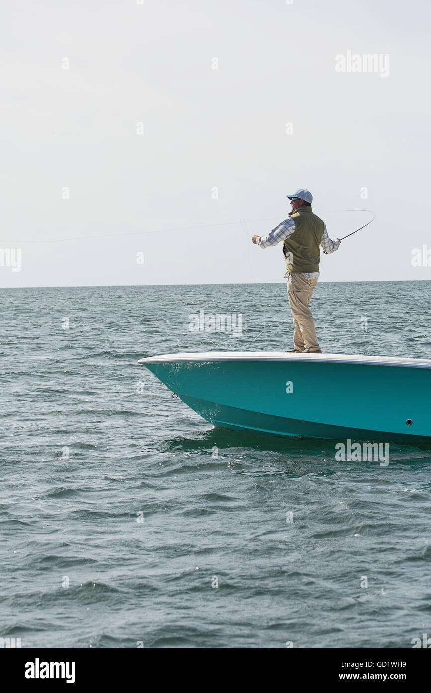 Un homme se tient ses lignes de pêche au large de l'avant d'un bateau sur la côte Atlantique, à Cape Cod, Massachusetts, USA Banque D'Images