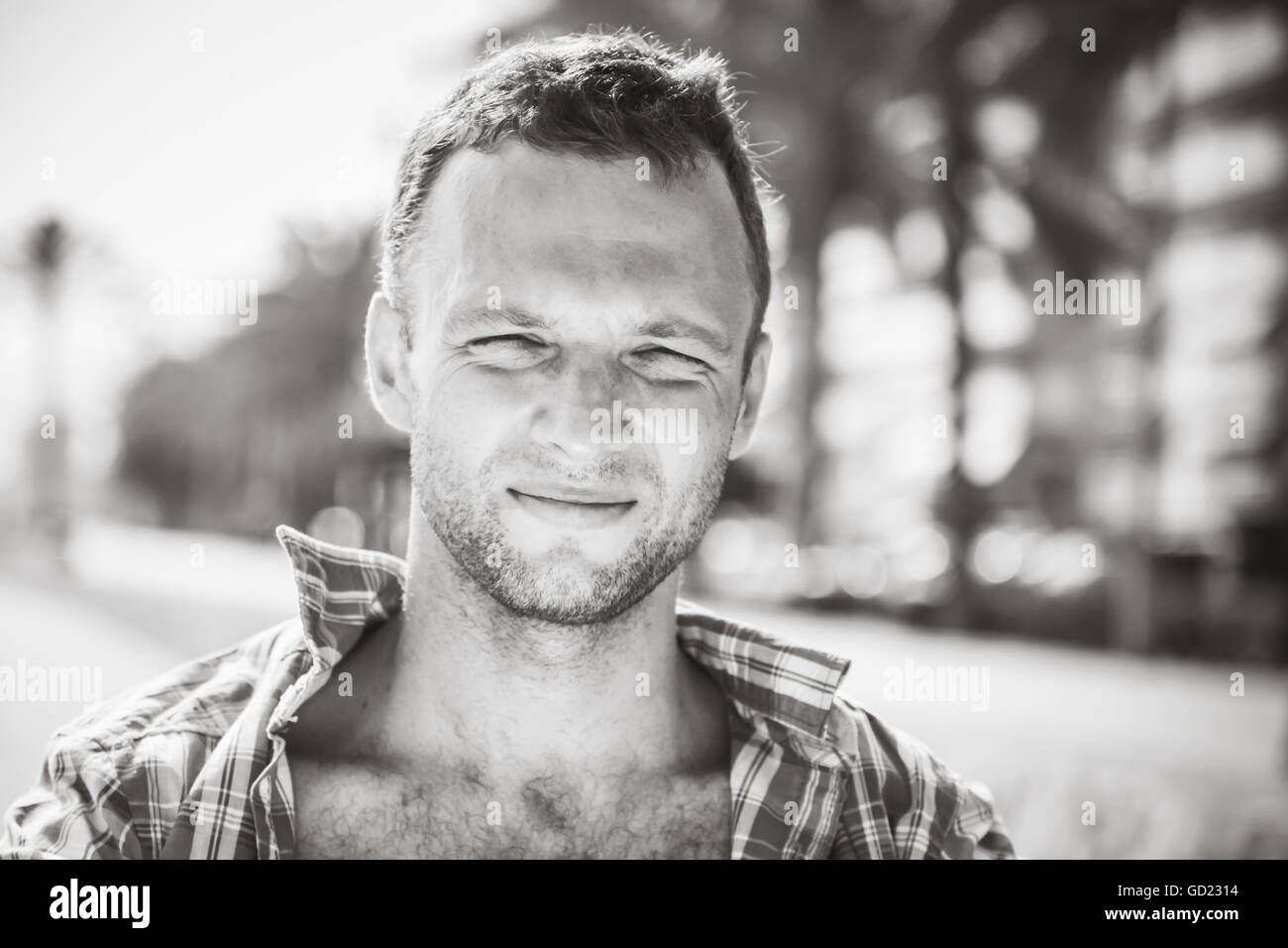 Smiling young handsome man, portrait en extérieur en journée ensoleillée, noir et blanc photo stylisée Banque D'Images