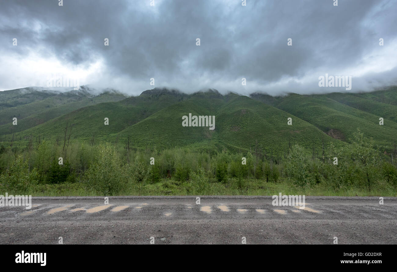Pluie nuages épais couvrir Peaceful Mounain Tops le long du côté de la route de gravier Banque D'Images