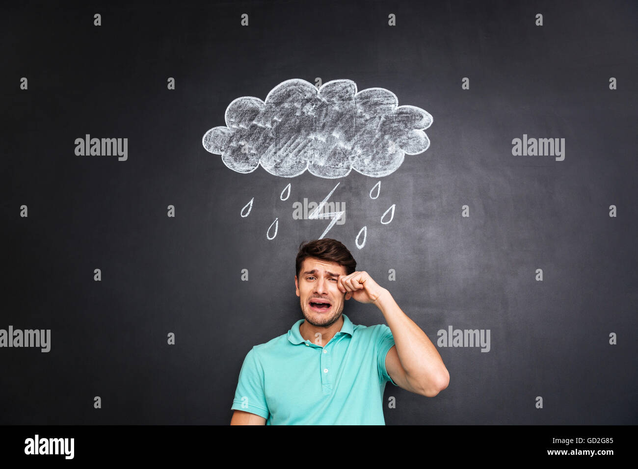 Jeune homme triste pleurer sur tableau noir avec appelée nuage Banque D'Images