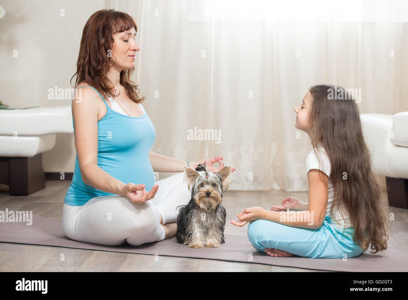 Concept de vie sain de la famille. La grossesse le yoga et la remise en forme. Les jeunes femmes enceintes maman pratiquant le yoga avec son chien et heureux kid girl Banque D'Images