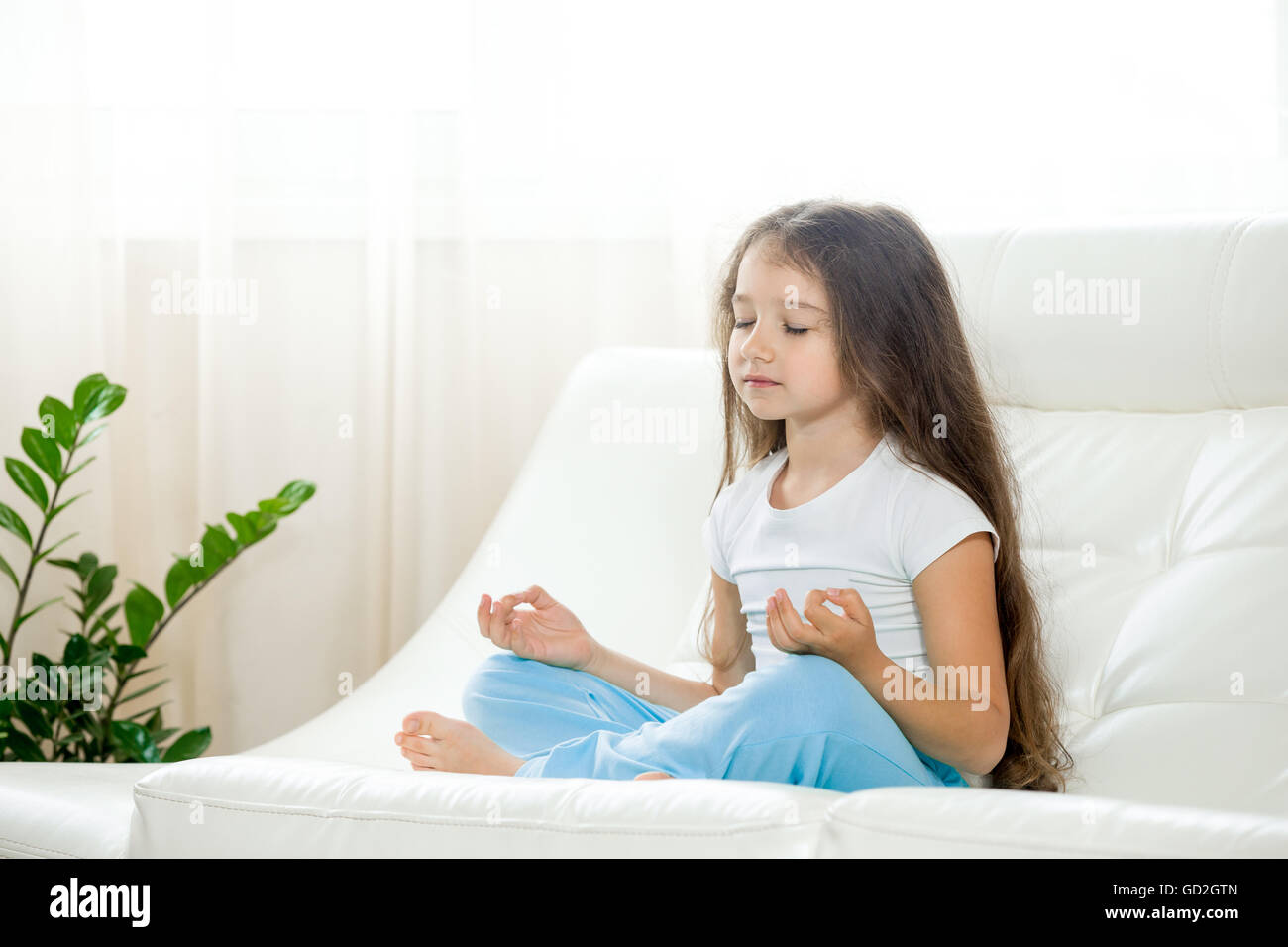 Concept de vie sain. Remise en forme et de yoga. Yoga serein little girl working out in living room sur blanc coach. Belle drôle Banque D'Images