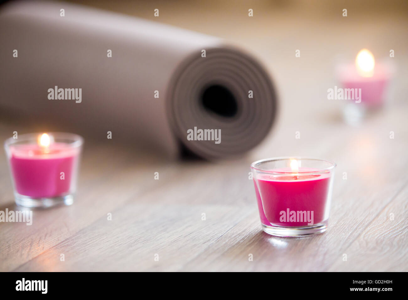 Éclairé de couleur rose bougie rose et marron laminé mat pilates, yoga sur le sol prêt à l'entraînement. Close up. La vie saine Banque D'Images