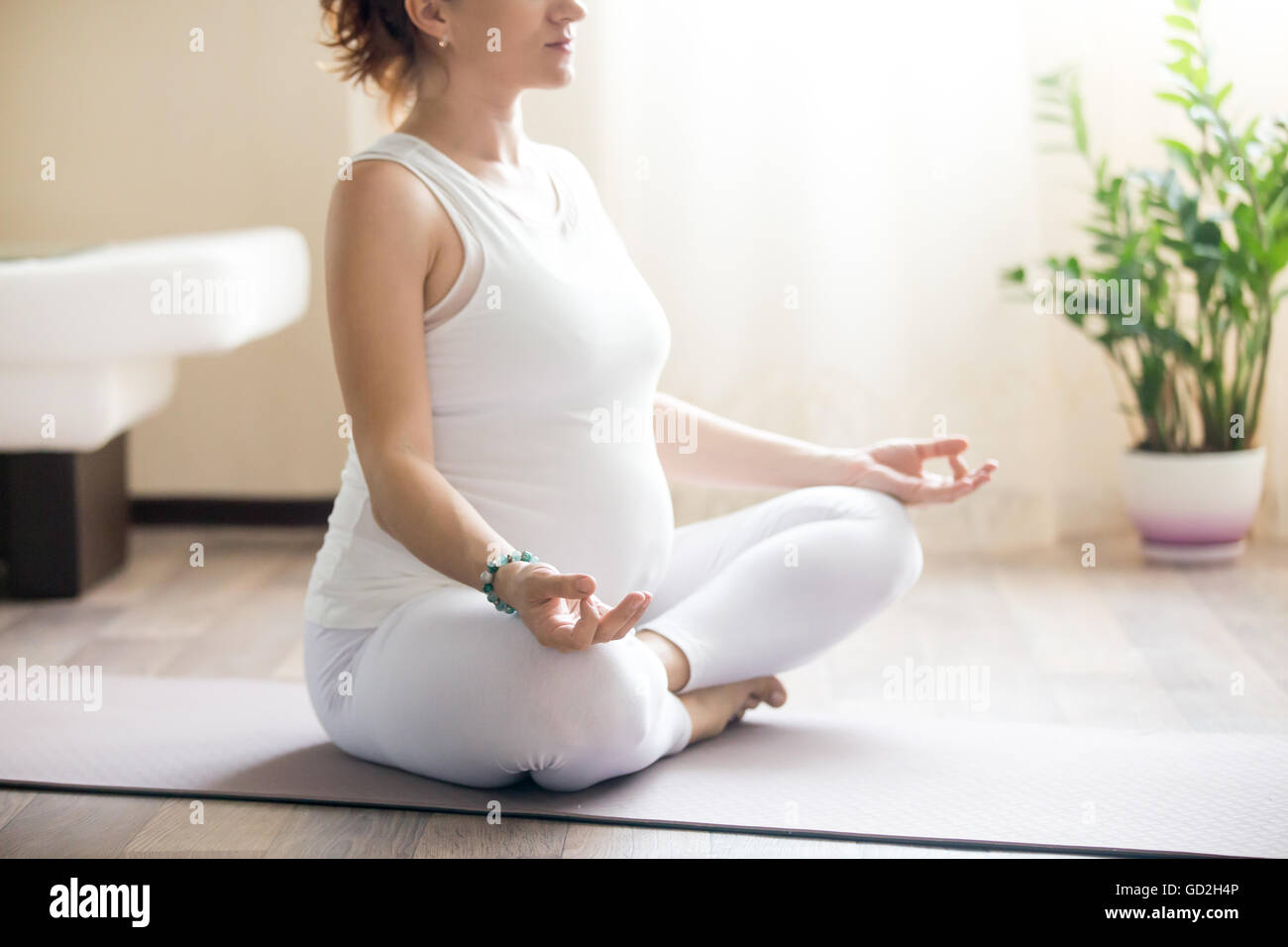 Grossesse en santé et de remise en forme de yoga. Les jeunes femmes enceintes yoga woman working out in living room interior. Modèle enceinte assis Banque D'Images