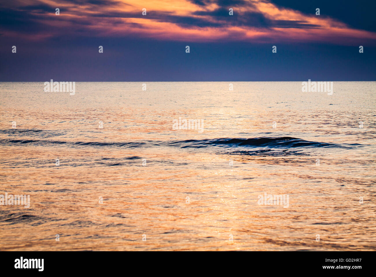 Seule petite vague à la surface de la mer calme au coucher du soleil. Banque D'Images